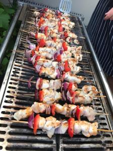 una fila de brochetas de pollo cocinando en una parrilla en The Chatsworth, en Weymouth