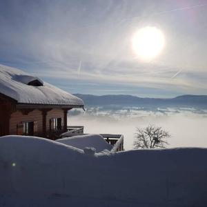 een huis bedekt met sneeuw met de zon op de achtergrond bij Les Genévriers in Foncine-le-Haut