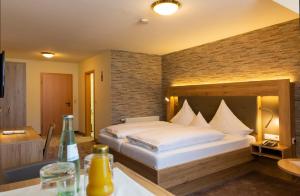 een slaapkamer met een groot bed met een bakstenen muur bij Land-gut-Hotel Räuber Lippoldskrug in Alfeld