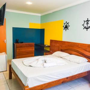 um quarto com uma cama com lençóis brancos e paredes coloridas em Casa Nui em Porto de Galinhas