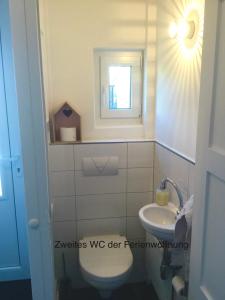 La salle de bains est pourvue de toilettes et d'un lavabo. dans l'établissement Ferienhaus Us lütt Hus und das Zimmer Linde im Haupthaus, à Oldenbourg