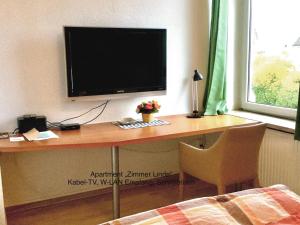 einen Schreibtisch mit einem TV an der Wand mit einem Stuhl in der Unterkunft Ferienhaus Us lütt Hus und das Zimmer Linde im Haupthaus in Oldenburg