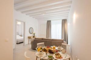 Vrisi/ Mykonos的住宿－Desire Mykonos Apartments，客厅配有沙发和餐桌,餐桌上摆放着食物