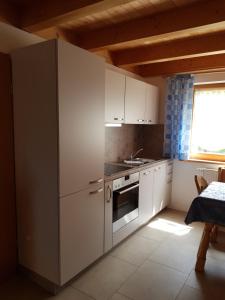 a kitchen with white cabinets and a stove and a window at Ferienhaus Sachrang in Sachrang