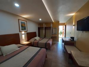 a hotel room with two beds and a flat screen tv at HOTEL MARIA TERESA in Playa Azul
