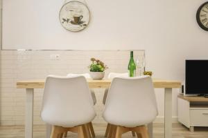 een tafel met twee witte stoelen en een fles wijn bij Apartamento Naypa with free parking in Cádiz