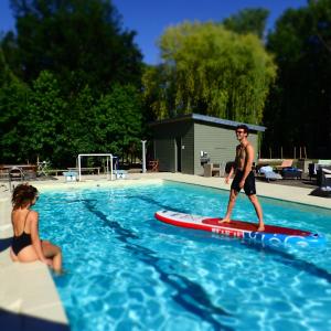 un homme debout sur une planche de surf dans une piscine dans l'établissement Les Bulles de la Maison du Rocher, à Noisy-sur-École