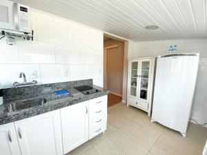 a white kitchen with a sink and a refrigerator at Ala Moana Pousada in Bombinhas