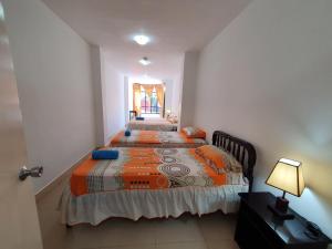 a bedroom with two beds and a lamp at Hostal Cerro Azul in Puerto Villamil