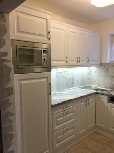 a kitchen with white cabinets and a microwave at Rózsa nyaralóház in Balatonboglár +44 photos