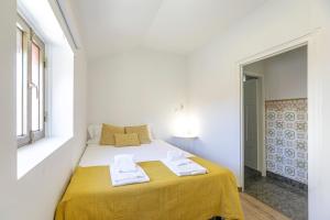 Cette chambre blanche comprend un lit avec des draps jaunes et une fenêtre. dans l'établissement LovelyStay - 1st A Mirante, à Porto