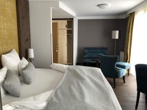 1 dormitorio con 1 cama blanca y 1 silla azul en Romantikhotel Residenz Wachau, en Aggsbach Dorf