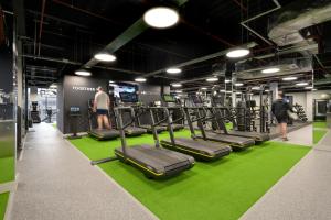 a gym with rows of tread machines on a green rug at Village Hotel Southampton Eastleigh in Southampton