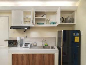 a kitchen with white cabinets and a black refrigerator at One Oasis By Paseo de Corazon Residence in Cagayan de Oro