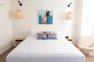 een wit bed in een witte slaapkamer met 2 hanglampen bij Endless Coast, A Boutique Hotel in Wellfleet