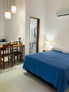 a bedroom with a blue bed and a table and chair at Chalés Caminhos do Cacau Camburi in Sao Paulo