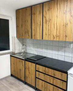 a kitchen with a sink and wooden cabinets at Modern Lux Apartment in Brčko
