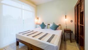 a bedroom with a large bed with blue pillows at Punto Mita Eco Surf Suites & Café in Punta Mita