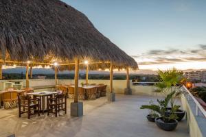 un restaurante con mesas y sillas y techo de paja en Punto Mita Suites, en Punta Mita