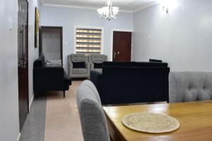 a living room with couches and a dining room table at Kay's ville Apartment in Abuja