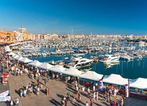 a group of people walking around a marina with boats at Villa émeraude dans résidence in Cap d'Agde