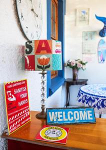 a table with a clock and a welcome sign on it at Mr Pell's House Self-Catering Accommodation in Jeffreys Bay