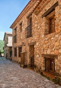 - un bâtiment en pierre avec des portes et des fenêtres donnant sur une rue dans l'établissement Casa Rural Campoamor, à Riópar