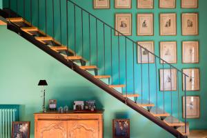 a wall of framed pictures on a green wall at Domaine de Labarthe Maison d'hotes in Espère