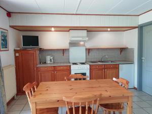 a kitchen with a wooden table with chairs and a television at Hotel Dry Les Courtis in Robertville