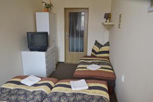 two beds in a small room with a television at Apartmán Náměstí Hostinné in Hostinné