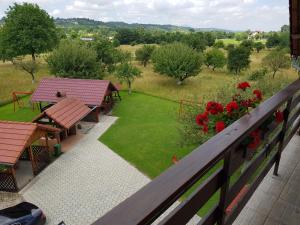 a balcony with picnic tables and a lawn with red flowers at Pensiunea din Livada in Bran