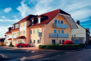 un bâtiment avec une voiture rouge garée devant lui dans l'établissement Hotel Waldeck Garni, à Kist