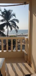 a balcony with a view of the beach and a palm tree at Baga Beach Exotica in Baga