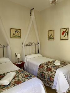 a bedroom with two beds and a chandelier at Pensión Cristina in El Rocío