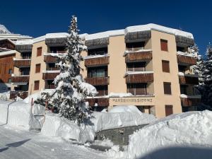 a snow covered building with a tree in front of it at Parsennresidenz in Davos