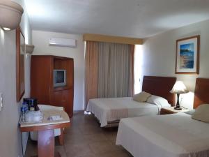 a hotel room with two beds and a television at HOTEL MARIA TERESA in Playa Azul