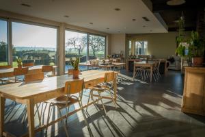 un ristorante con tavoli e sedie in legno e ampie finestre di B&B Buytenshuys a Hooglede