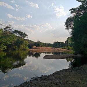 a river with trees and clouds in the water at Pousada Serra Da Canastra in Vargem Bonita