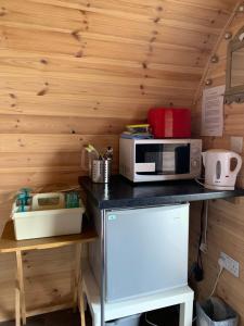 a kitchen with a counter with a microwave and a refrigerator at Poplars Farm Site Glamping Pods Adults only with separate, private shower rooms in Hulland