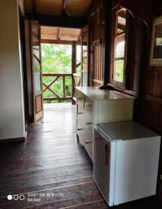 a kitchen with a refrigerator and an open door at Pousada Kalua Praia in Garopaba