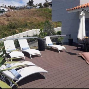 a group of lounge chairs on a deck with an umbrella at Villa Sol e Mar Garajau Madeira in Caniço