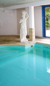 uma estátua de uma mulher ao lado de uma piscina em Le Manoir de la mantille em Caudry