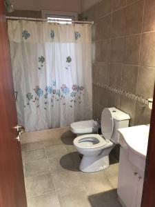 a bathroom with a toilet and a shower curtain at Casa Juno Pinamar Norte in Pinamar