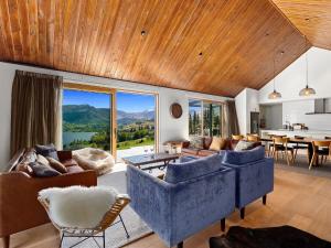 una sala de estar con muebles azules y una gran ventana. en Sicilian Luxury Retreat, en Queenstown