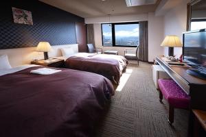 a hotel room with two beds and a flat screen tv at Hotel Sun Hitoyoshi in Hitoyoshi