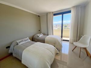 a bedroom with two beds and a chair and a window at Constantino V in Villa Carlos Paz +261 photos