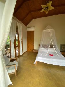 a bedroom with a bed with a mosquito net at Waterfall Accomodation in Port Glaud