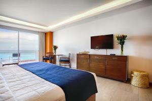 a bedroom with a large bed and a flat screen tv at The Paramar Beachfront Boutique Hotel With Breakfast Included - Downtown Malecon in Puerto Vallarta