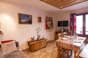 een woonkamer met een tafel en een televisie bij La Soldanelle in Lanslevillard