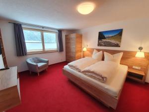 a bedroom with a bed and a chair and a window at Appartements Gamsblick in Pettneu am Arlberg